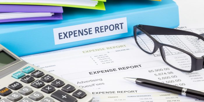 Business expense report binder with financial documents and calculator